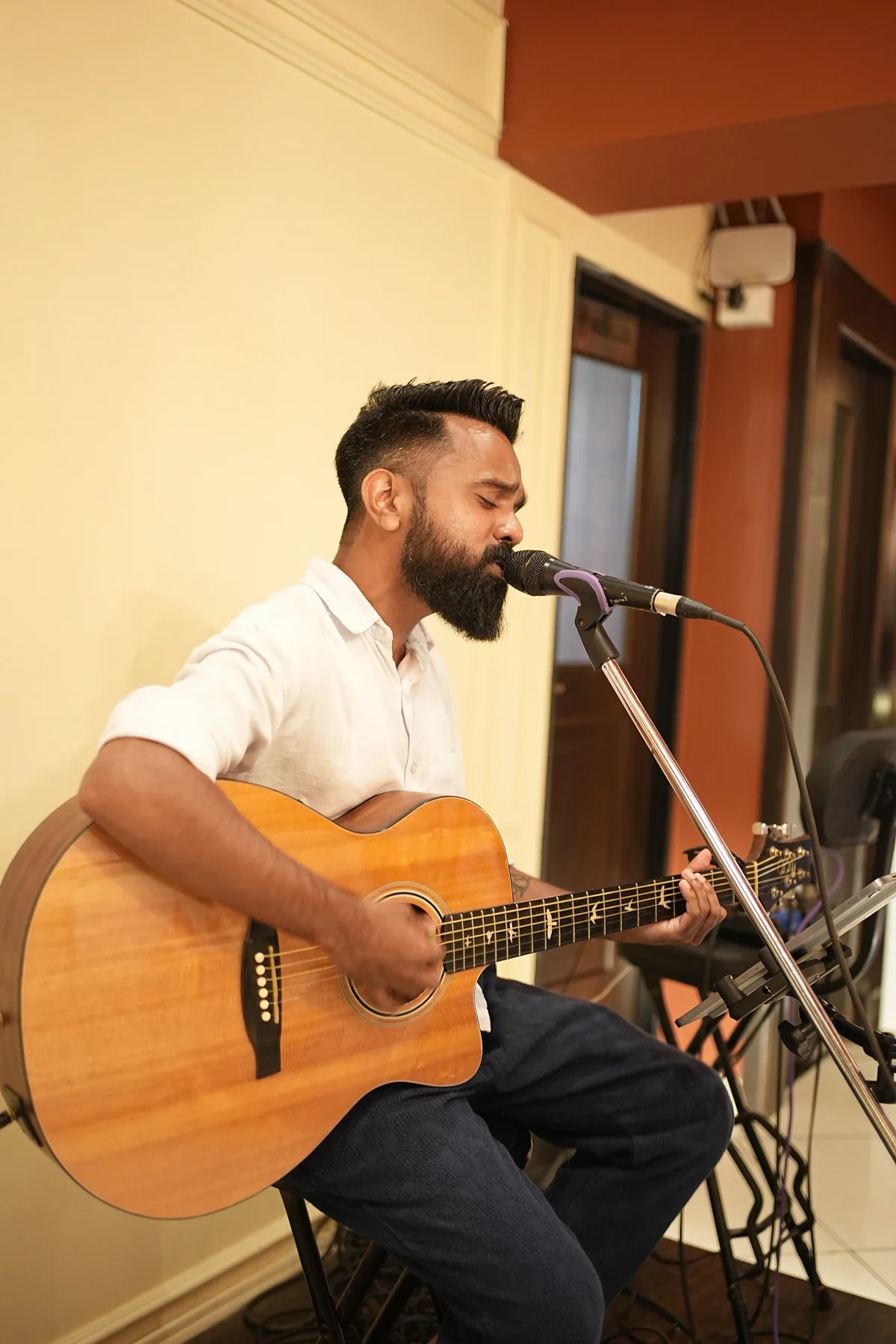 A singer performing with an acoustic guitar and microphone at RHYTHM