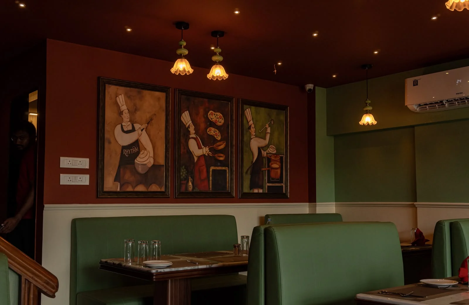 A welcoming green booth and set table below framed artwork at RHYTHM