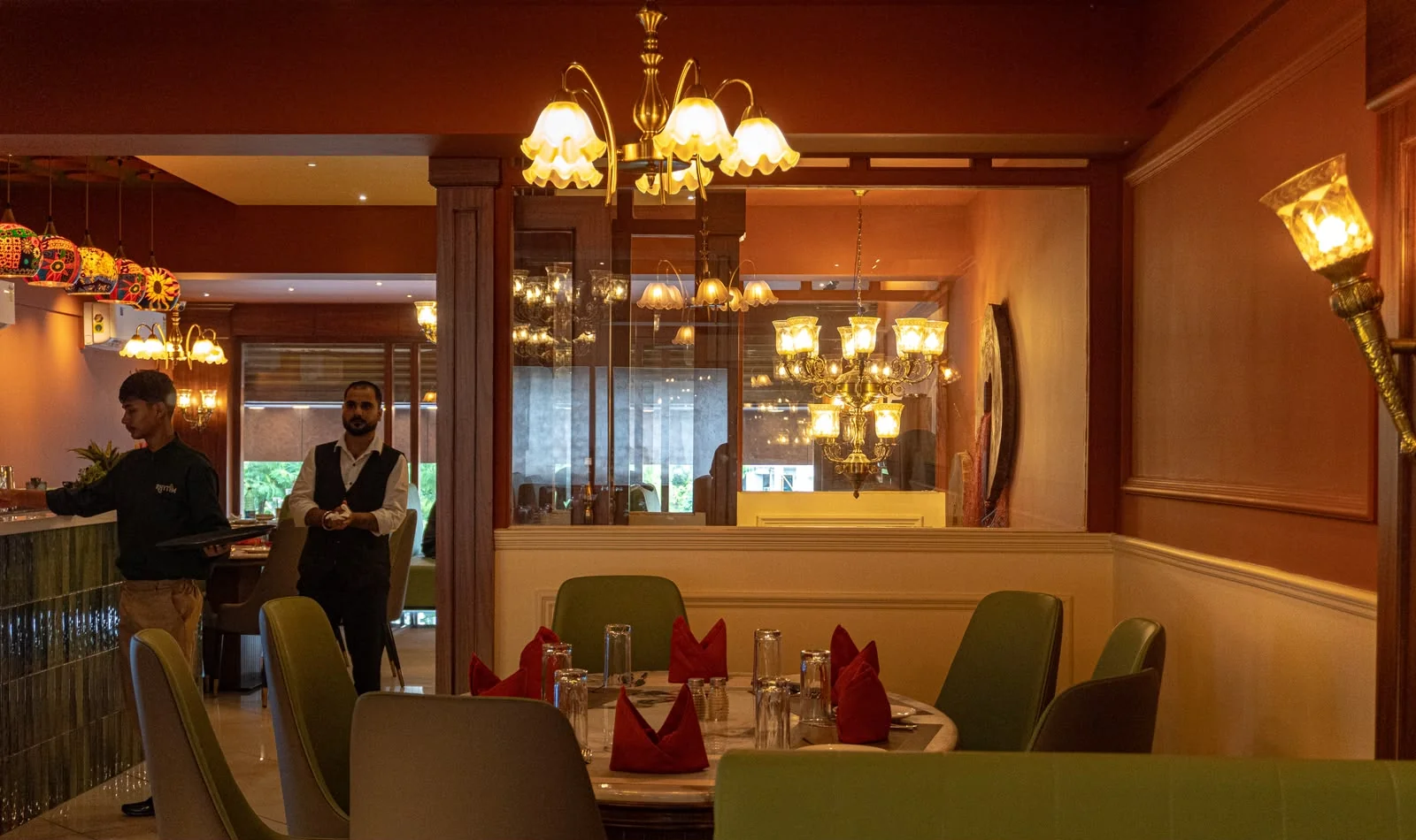 RHYTHM’s terracotta dining room with warm chandeliers, walnut wood and green seating
