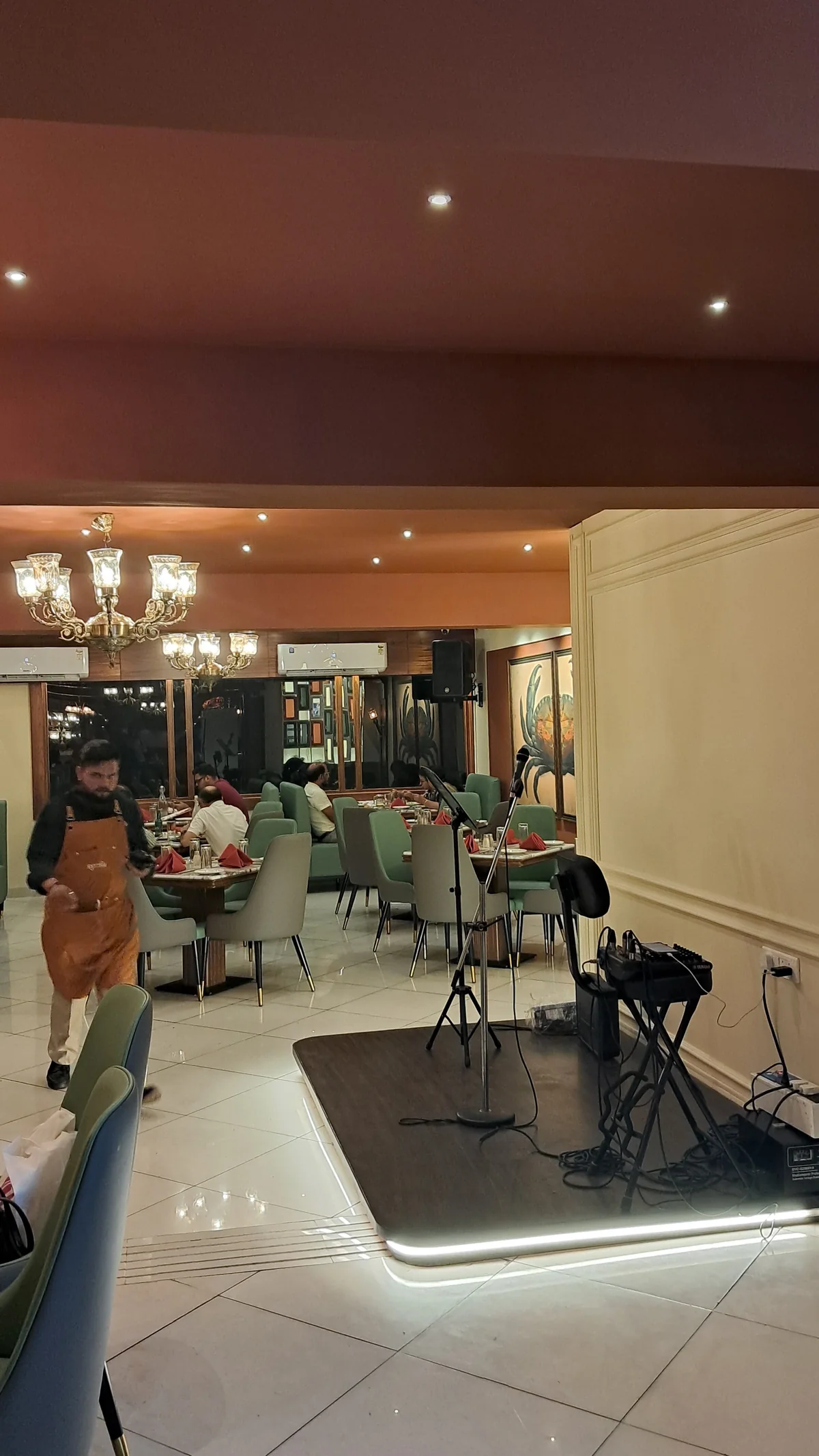 The intimate music stage at RHYTHM with microphones and a keyboard beside the dining room