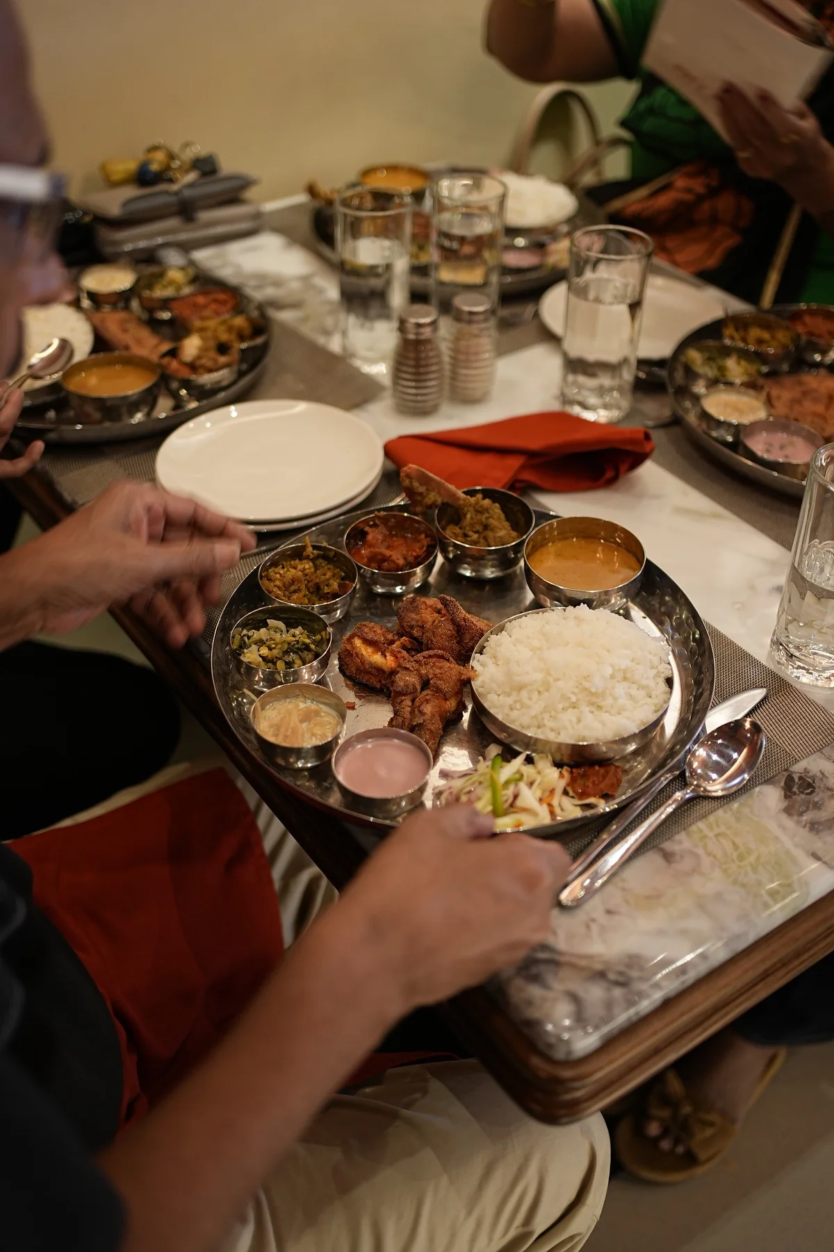 Guests sharing thalis and conversation around a marble table at RHYTHM